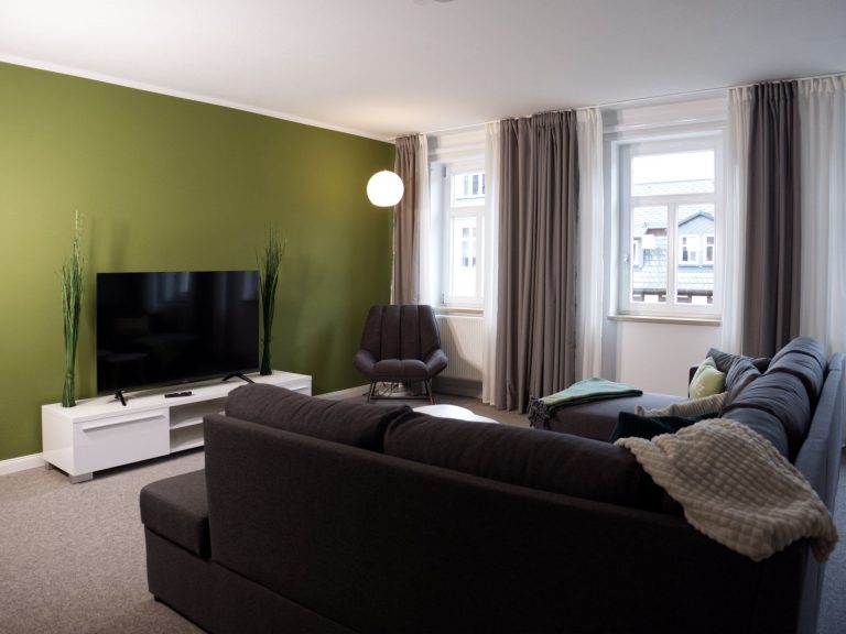 Helles Wohnzimmer mit großem Fernseher und Sitzgruppe des Apartments Boulevard XXL.