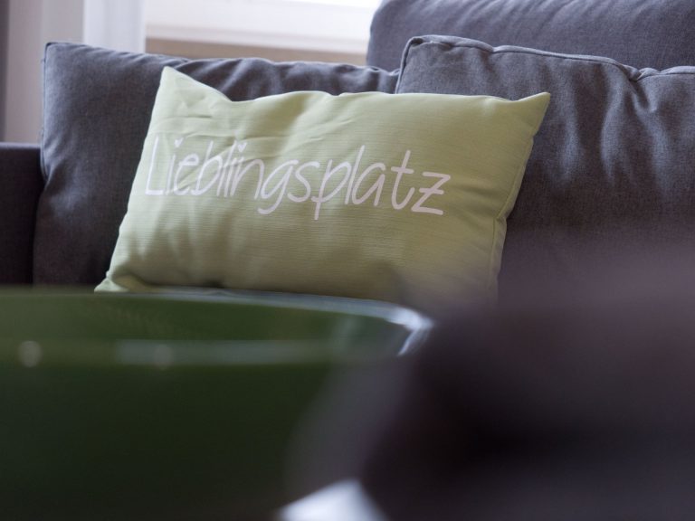 Kissen mit Aufschrift "Lieblingsplatz" auf dem Sofa im Apartment Boulevard XXL.