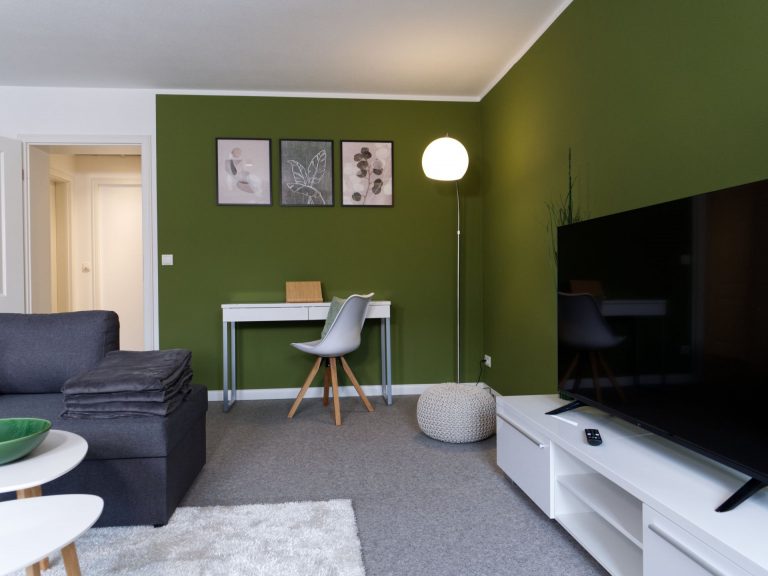 Fernseher, Schreibtisch und Sofa im Wohnzimmer des Apartment Boulevard XXL.